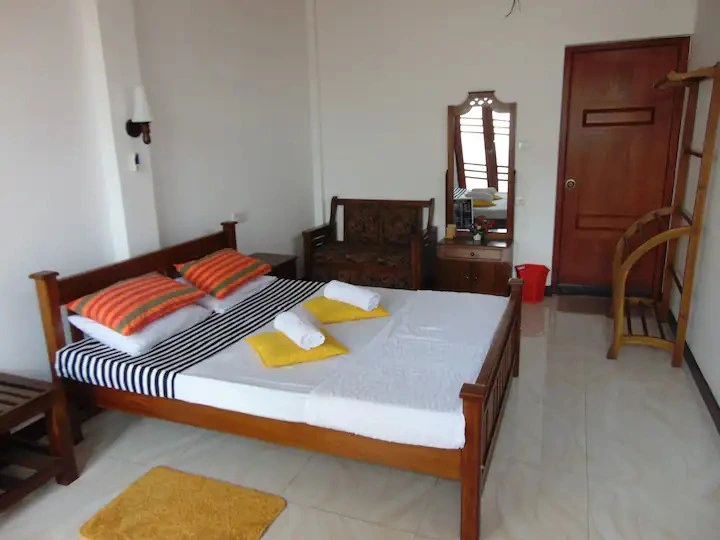 Deluxe Family Room with a wooden double bed, orange and yellow bedding, carved armchair and dressing mirror