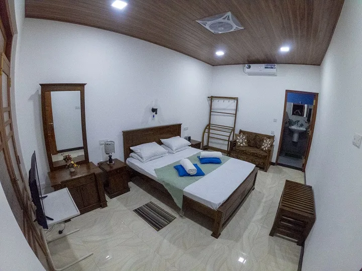 Deluxe Triple Room with a timber ceiling, ceiling fan, wall-mounted air conditioning and the en-suite bathroom beyond