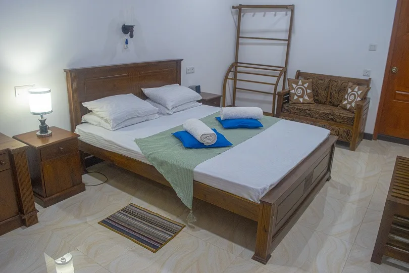Deluxe Triple Room sleeping area with the queen and single beds side by side, next to carved wooden seating
