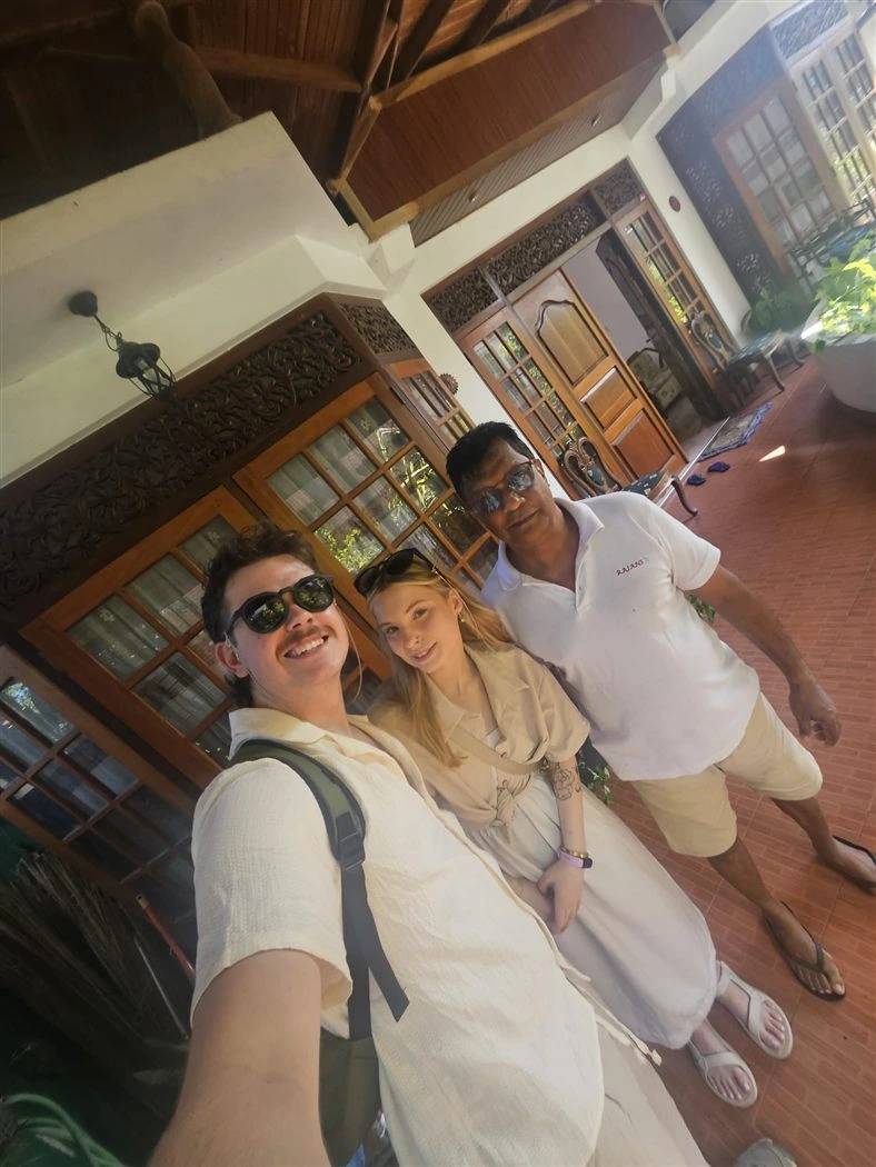 Guests taking a selfie with their host on the veranda by the carved wooden doors