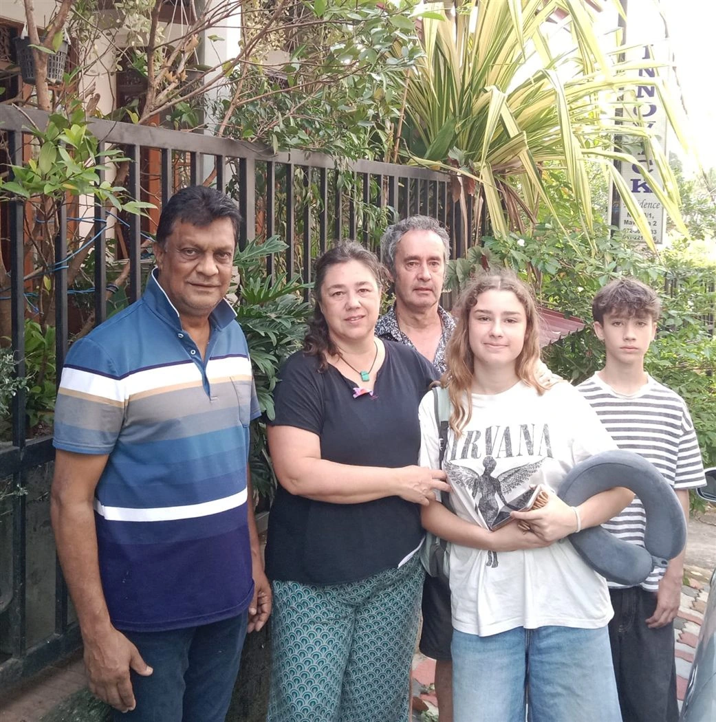 A family of guests with their host at the entrance, beside the Innovick Residence sign