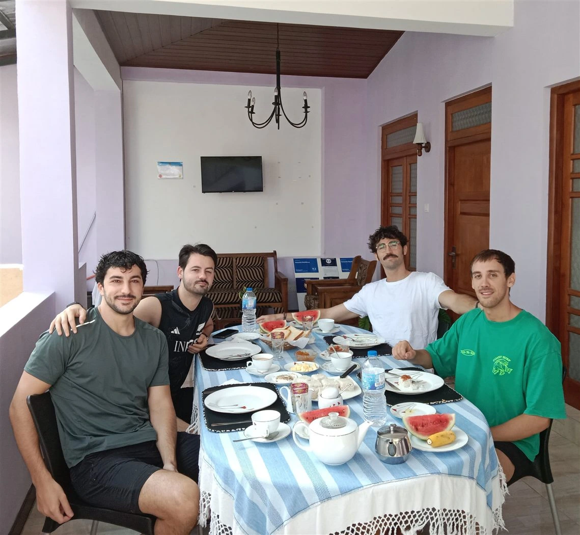 Four guests around the breakfast table with watermelon, string hoppers and tea