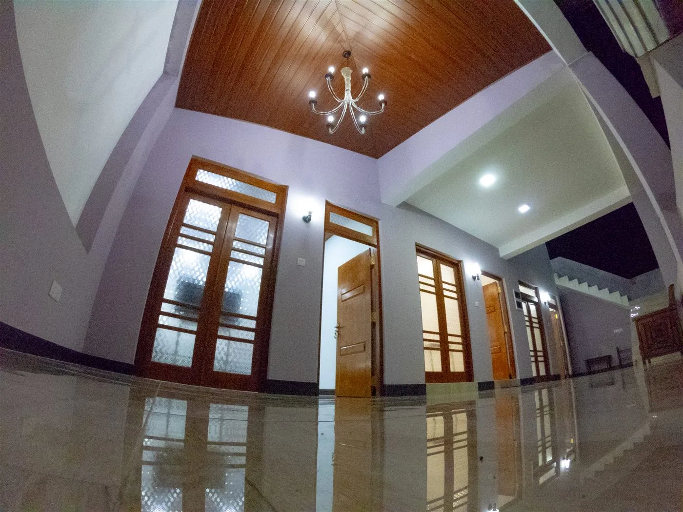 Interior landing with polished floors, timber ceiling, chandelier and guest room doors