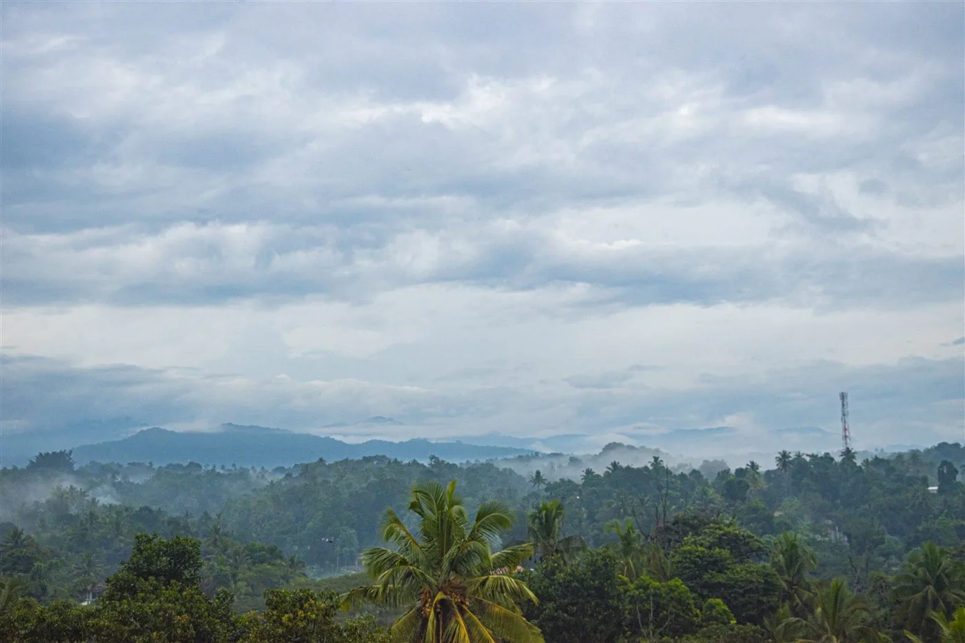 Cloud and mist hanging over the wooded hills and palms around Aruppola