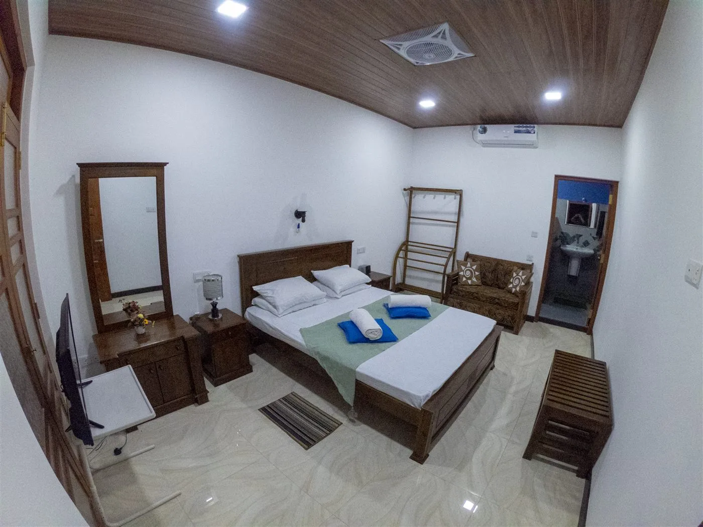 Deluxe air-conditioned guest bedroom interior with queen bed and wooden furnishings