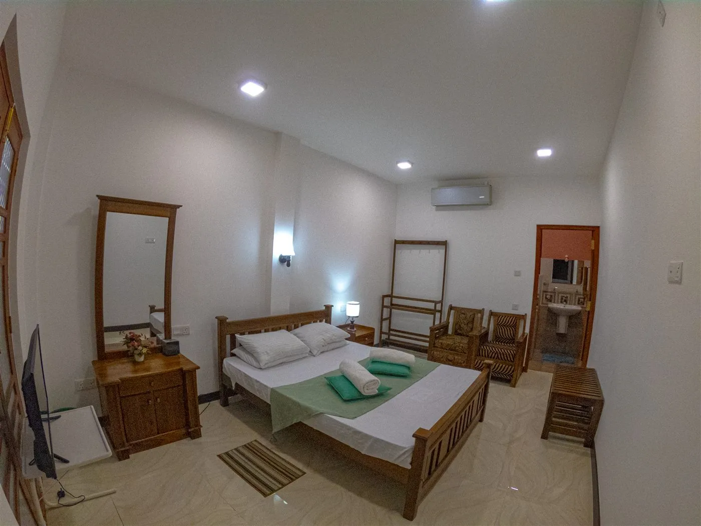Guest bedroom with wooden bed frame, air conditioning and the en-suite bathroom beyond